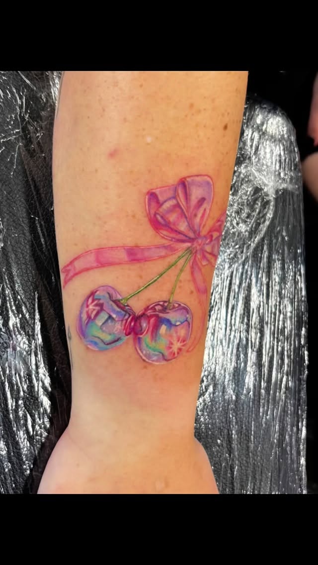 Iridescent color cherry and bow wrist tattoo